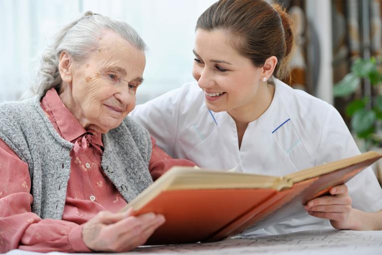 Elderly woman and carer reading