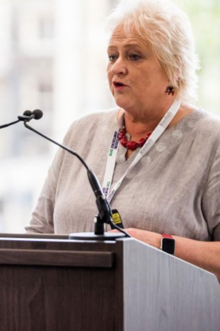 Anne Kelly speaking at podium