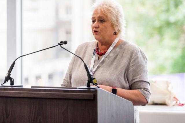 Anne Kelly Speaking at a Podium