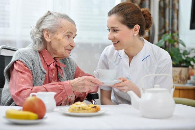 Elderly woman and carer having tea