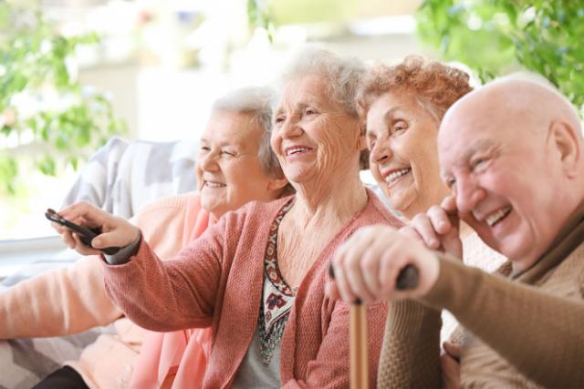 Elderly group laughing watching televsion