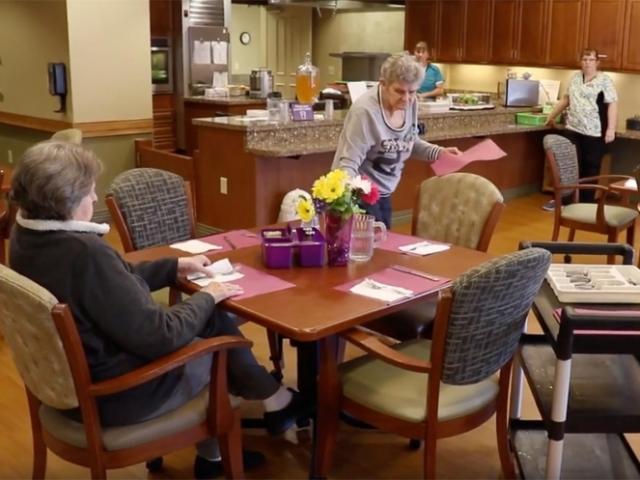 Elderly woman setting the table in an aged care facility
