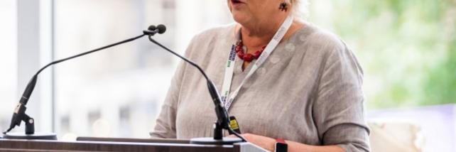 Anne Kelly Speaking at a Podium