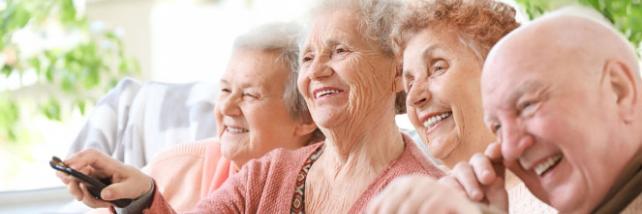 Elderly group laughing watching televsion