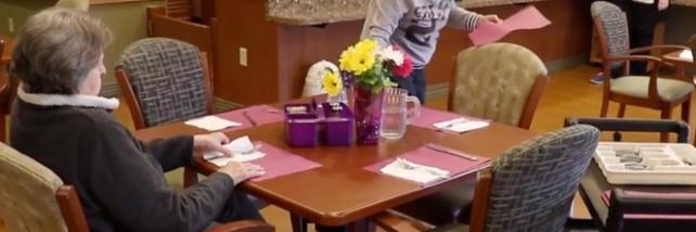 Elderly woman setting the table in an aged care facility